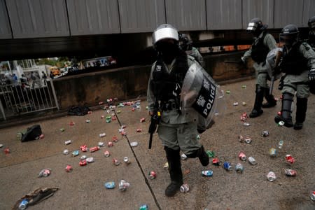 Riot police walk on a road littered with cans in Kowloon district, in Hong Kong