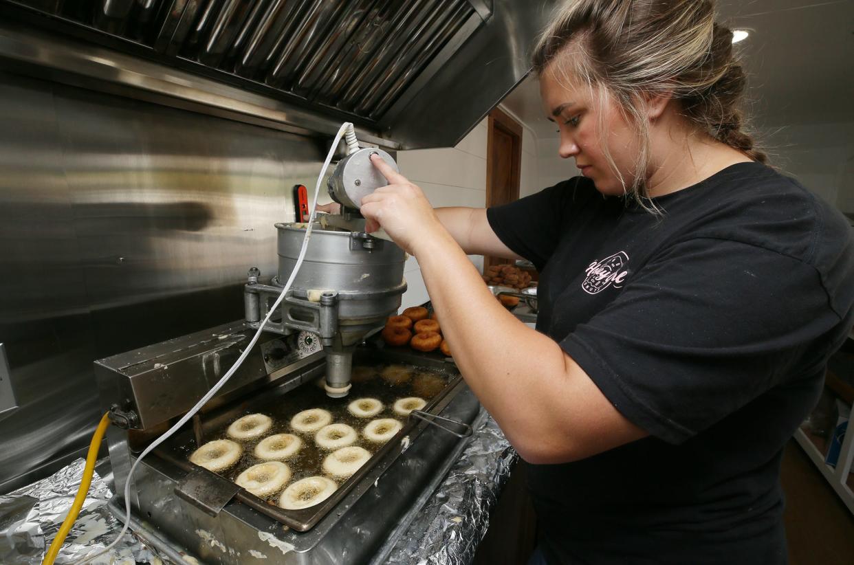 Katie Vasiloff, co-owner of Honey Girl Donuts, makes a fresh batch of doughnuts in the custom trailer outside of Lowes in Brimfield on Saturday.