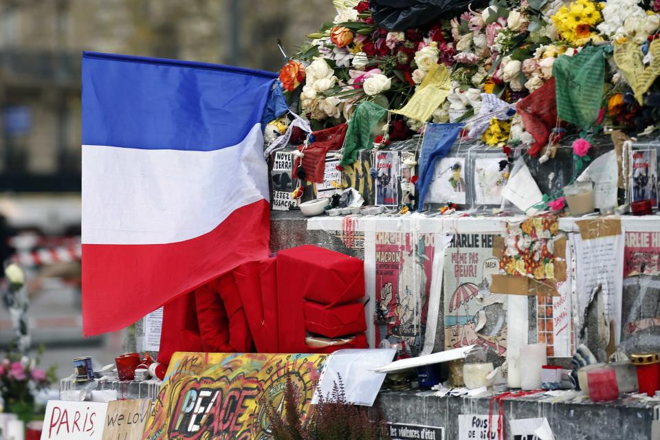 A French flag is seen among candles, flowers and messages in tribute to victims at the Place de la Republique in Paris, France November 26, 2015. The French President called on all French citizens to hang the tricolour national flag from their windows on Friday to pay tribute to the victims of the Paris attacks. (REUTERS/Charles Platiau)