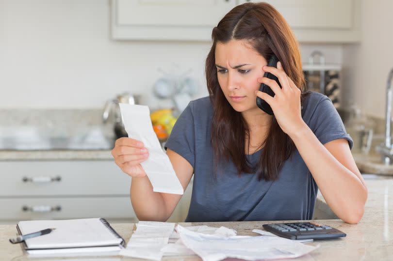 Thinkstock generic image of a Woman making a call on her mobile phone while calculating her bills