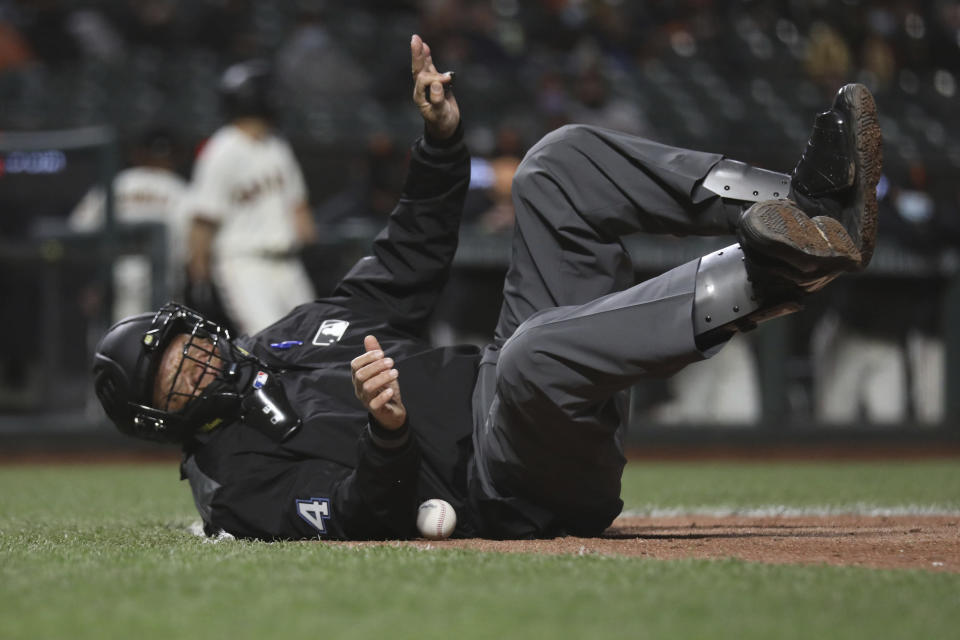 Home plate umpire Kerwin Danley is knocked down by a ball during the sixth inning of a baseball game between the Colorado Rockies and San Francisco Giants in San Francisco, Tuesday, April 27, 2021. (AP Photo/Jed Jacobsohn)