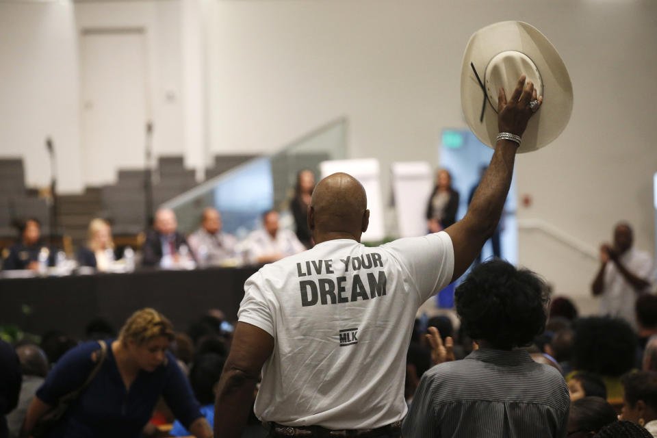 A Phoenix resident stands up to wave his cowboy hat in support of a speaker at a community meeting, Tuesday, June 18, 2019, in Phoenix. The community meeting stems from reaction to a videotaped encounter that surfaced recently of Dravon Ames and his pregnant fiancee, Iesha Harper, having had guns aimed at them by Phoenix police during a response to a shoplifting report, as well as the issue of recent police-involved shootings in the community. (AP Photo/Ross D. Franklin)