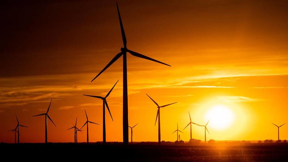 The sun sets on a field of wind turbines at a wind farm in Indiana, United States.