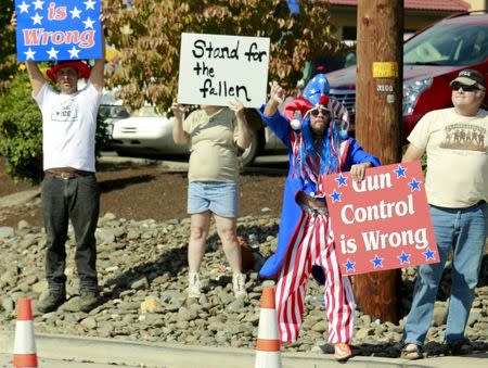 Pro-gun protesters hold signs as U.S. President Barack Obama's motorcade passes upon his arrival in Roseburg, Oregon October 9, 2015. REUTERS/Kevin Lamarque