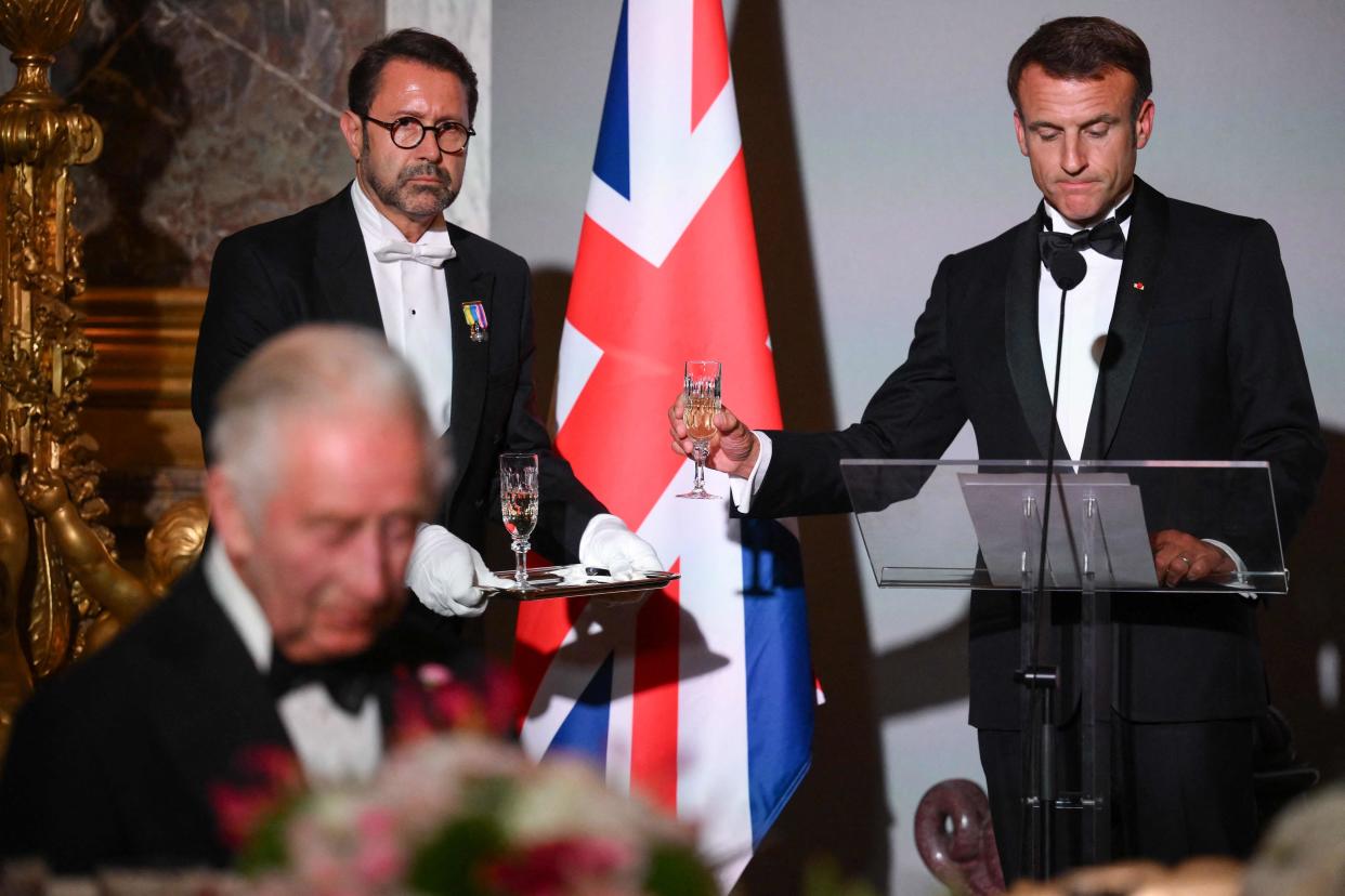 French President Emmanuel Macron (R) is handed a glass before his speech (POOL/AFP via Getty Images)