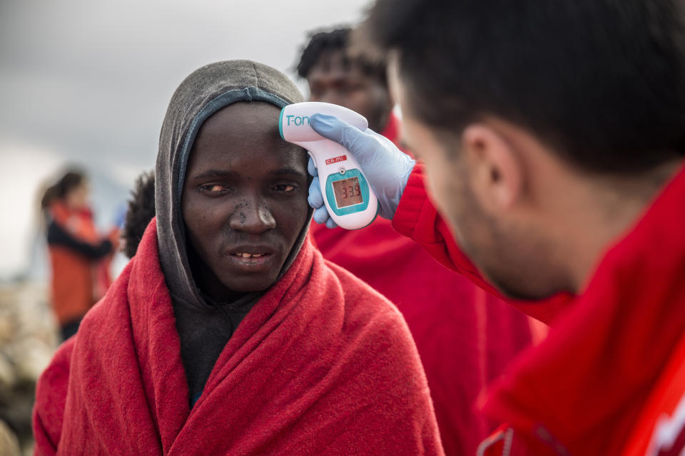 A volunteer takes the temperature of a migrant after disembarking from the Spanish NGO Proactiva Open Arms rescue vessel, after being rescued Dec. 21, in the Central Mediterranean Sea, before disembarking in the port of Crinavis in Algeciras, Spain, Friday, Dec. 28, 2018. The Proactiva Open Arms aid boat carrying over 300 migrants rescued at sea, has ended a weeklong journey across the western Mediterranean Sea to dock at the Spanish port of Algeciras on Friday. (AP Photo/Olmo Calvo)