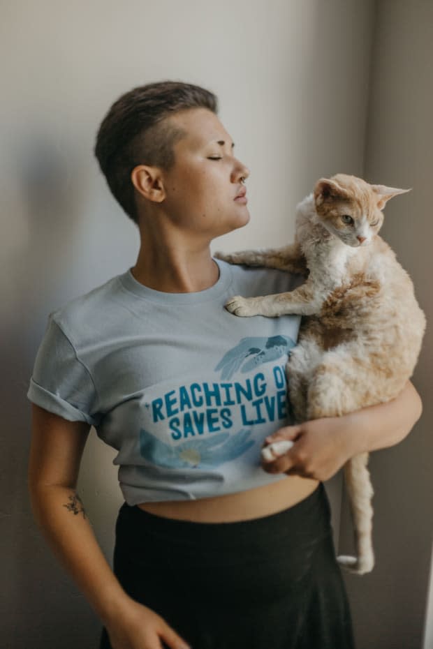 <em>Self-Care Is for Everyone's </em><a href="https://selfcareisforeveryone.com/products/reaching-out-saves-lives-supporting-the-national-suicide-prevention-lifeline-t-shirt" rel="nofollow noopener" target="_blank" data-ylk="slk:"Reaching Out Saves Lives" T-shirt;elm:context_link;itc:0;sec:content-canvas" class="link "><em>"</em>Reaching Out Saves Lives" T-shirt</a>, supporting the National Suicide Prevention Lifeline.