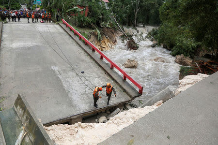 Members of Guatemalan emergency commission (CONRED) stand at a bridge that collapsed after heavy rains brought by Hurricane Earl at Menchor de Mencos, Guatemala, August 4, 2016. REUTERS/Luis Echeverria