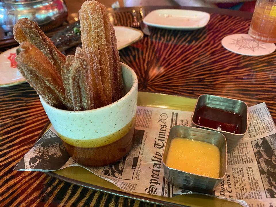Churros served on a tray next to two dipping sauces
