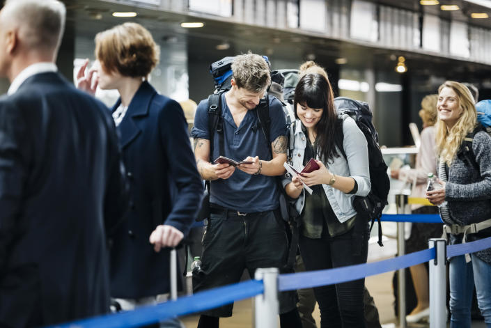 Young backpackering couple checking mobile boarding pass on smart phone
