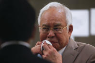 Former Malaysia Prime Minister Najib Razak, centre, wipes his sweat before leaving the Kuala Lumpur High Court complex in Kuala Lumpur, Malaysia, Tuesday, July 28, 2020. The court has sentenced Razak to serve 12 years in prison after finding him guilty in the first of several corruption trials linked to the multibillion-dollar looting of a state investment fund that brought down his government two years ago. (Fazry Ismail/Pool Photo via AP)