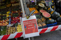 A sign of social distancing guidelines hangs on a street stall in a market in Madrid, Spain, Tuesday, Oct. 13, 2020. The sign reads in Spanish "Remember, keep a safe distance 2 meters". (AP Photo/Bernat Armangue)