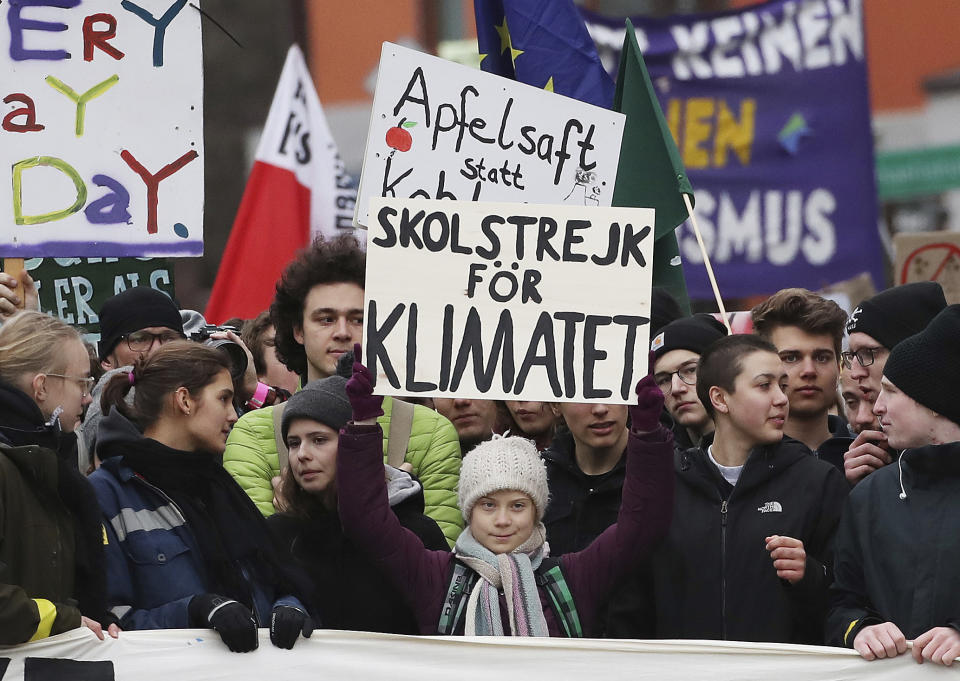 FILE - In this Friday, Feb 21, 2020 file photo Climate avtivist Greta Thunberg, center, from Sweden lifts a poster as she takes part in a protest rally of the 'Fridays For Future' movement in Hamburg, Germany. In a wide-ranging monologue on Swedish public radio, teenage climate activist Greta Thunberg recounts how world leaders queued up to have their picture taken with her even as they shied away from acknowledging the grim scientific fact that time is running out to curb global warming. (Christian Charisius/dpa via AP, file)