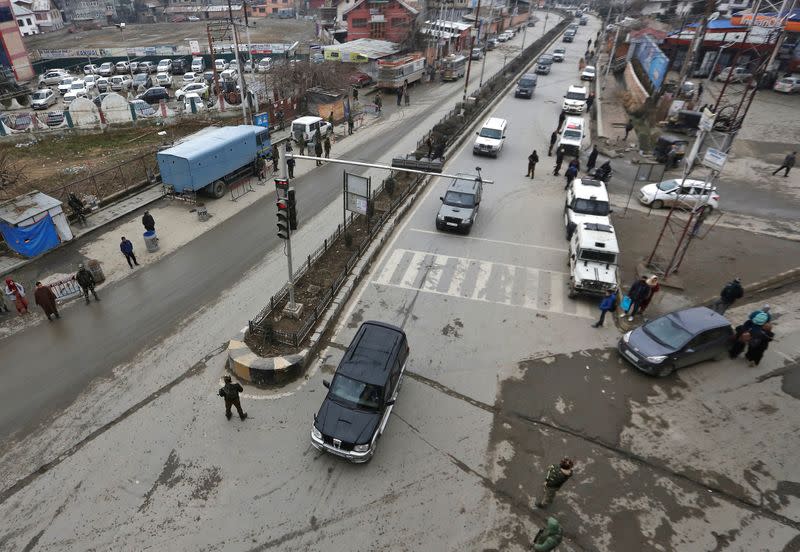 Indian security personnel stand guard as a convoy believed to be transferring foreign diplomats moves in Srinagar