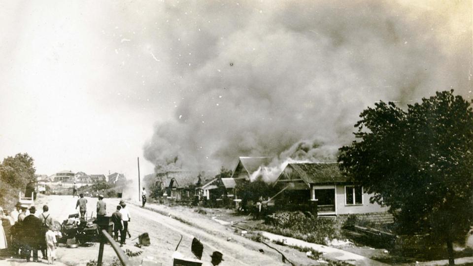 PHOTO: A group of people looking at smoke in the distance coming from damaged properties following the Tulsa Race Massacre, Tulsa, Oklahoma, June 1921. (Oklahoma Historical Society/Getty Images)