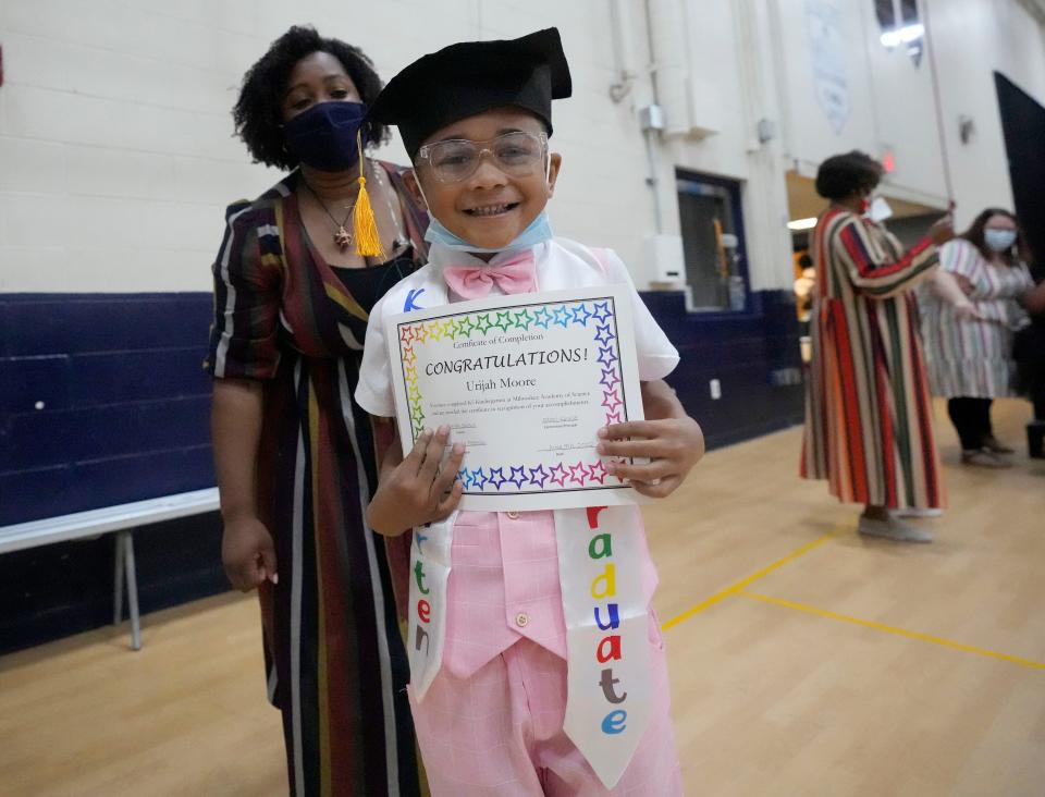 K-5 graduate Urijah Moore poses with his certificate as assistant principal Kimberly Peterson looks on during a K-5 promotion ceremony at the Milwaukee Academy of Science, on West Kilbourn Avenue in Milwaukee on Thursday. Students were selected to be a part of the "I Have A Dream" college scholarship program which provides students and their families with 12 years of support services and a $10,000 college scholarship.