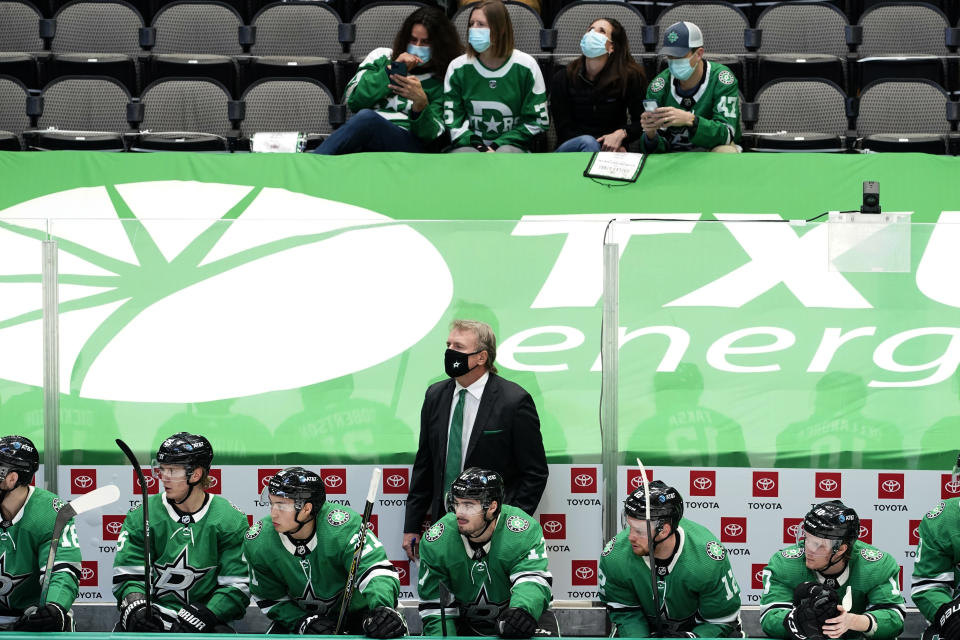 Dallas Stars coach Rick Bowness stands behind players as fans sitting a distance away watch the first period of the team's NHL hockey game against the Nashville Predators in Dallas, Friday, Jan. 22, 2021. (AP Photo/Tony Gutierrez)