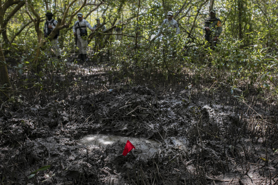 Soldiers of the Mexican Army and members of the National Guard stand next to a clandestine grave site in Puquita, a tropical mangrove island near Alvarado in the Gulf coast state of Veracruz, Mexico, Thursday, Feb. 18, 2021. Investigators from the National Search Commission found three pits with human remains and plastic bags inside. The number of bodies there has not yet been determined. (AP Photo/Felix Marquez)