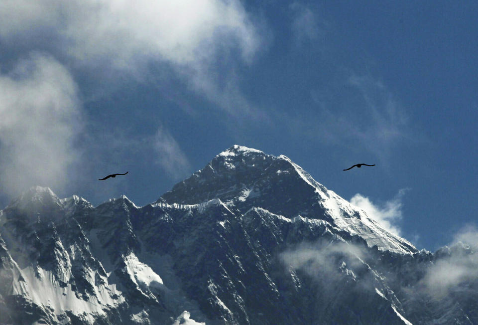 Birds fly as Mount Everest is seen from Namche Bajar, Solukhumbu district, Nepal, Monday, May 27, 2019. A Colorado climber died shortly after getting to the top of Mount Everest and achieving his dream of scaling the highest peaks on each of the seven continents, his brother said Monday. (AP Photo/Niranjan Shrestha)
