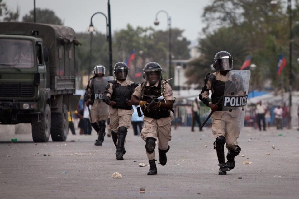 Police officers rush protestors on the street firing tear gas directly in front of the National Palace as protestors took to the streets to demand that Haitian President Rene Preval leave office February 7, 2011 in Port-au-Prince, Haiti. (Photo by Allison Shelley/Getty Images)