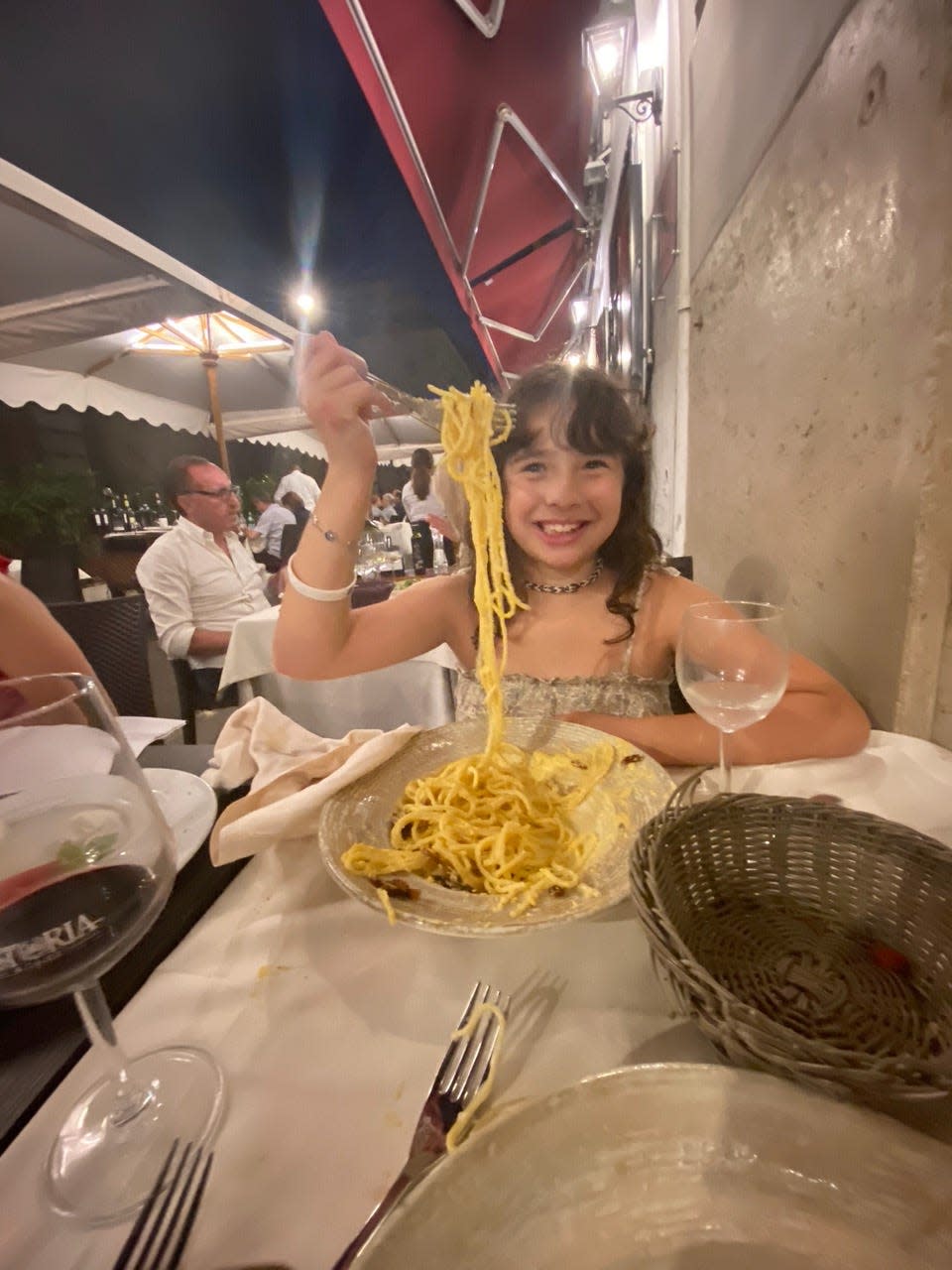 The author's daughter holding up a bite of cacio e pepe at a restaurant in Rome.