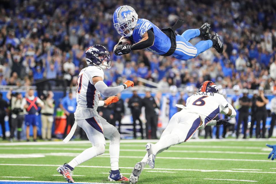 Detroit Lions wide receiver Amon-Ra St. Brown dives for a touchdown over Denver Broncos safety P.J. Locke during the first half at Ford Field in Detroit on Saturday, Dec. 16, 2023.