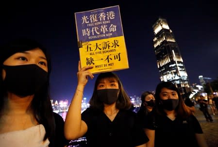 A woman holds a placard as protesters form a human chain during a rally to call for political reforms at Tsim Sha Tsui and Hung Hom Promenade in Hong Kong