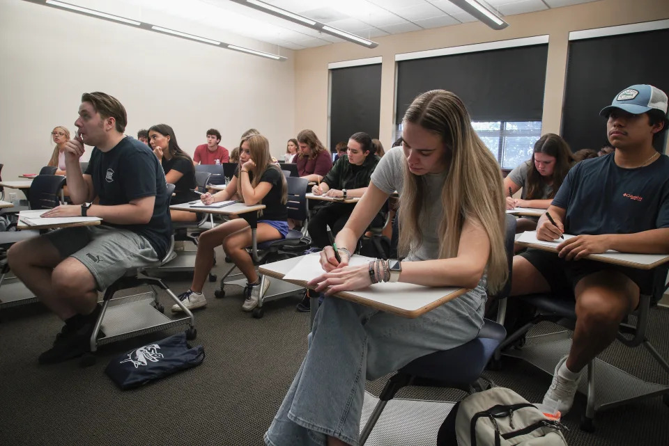 Audra Hillman, 18, foreground right, a freshman at the University of South Carolina Beaufort, takes a modified citizenship quiz during an American government class in Bluffton, S.C., on Tuesday, Aug. 20, 2024. (AP Photo/Allen G. Breed)