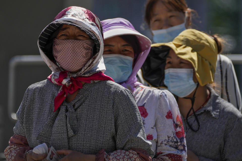 Women wearing face masks wait in line to get their routine COVID-19 throat swabs at a coronavirus testing site in Beijing, Tuesday, Sept. 20, 2022. (AP Photo/Andy Wong)