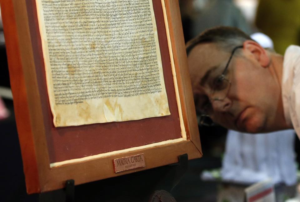 A judge examines a cake in the shape of the Magna Carta on the opening day of the Cake International show in Manchester, northern England, February 6, 2015. REUTERS/Phil Noble (BRITAIN - Tags: SOCIETY FOOD)