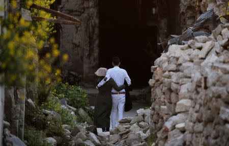 A couple walks on rubble of damaged shops in the old city of Aleppo, Syria April 12, 2019. Picture taken April 12, 2019. REUTERS/Omar Sanadiki