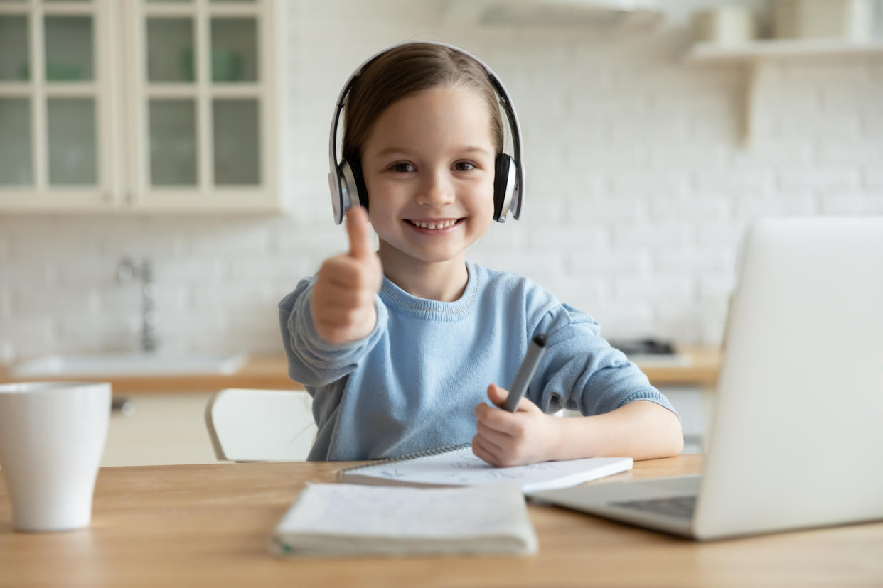 Portrait of excited little girl in headphones show thumb up 