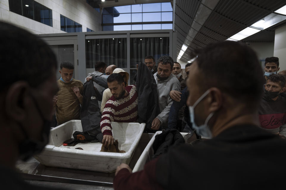 Palestinian workers crossing from Gaza to Israel wait for their belongings after a security check on the Israeli side of Erez crossing between Israel and the Gaza Strip, March. 27, 2022. Israel said it will reopen its crossing with the Gaza Strip to Palestinian workers on Tuesday, April 26, 2022, after it had been closed for several days following rocket attacks from the Palestinian enclave. Israel has issued thousands of work permits to Palestinians from Gaza, which has been under a crippling Israeli and Egyptian blockade since Hamas seized power from rival Palestinian forces nearly 15 years ago. (AP Photo/Oded Balilty)