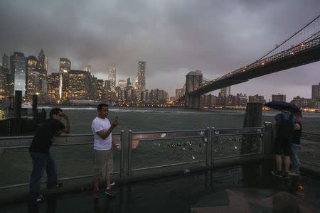 Tourists stand underneath the Brooklyn Bridge to photograph a summer storm bearing down on New York July 2, 2014. REUTERS/Lucas Jackson