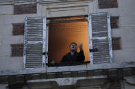 French tenor singer Stephane Senechal sings from his apartment window in Paris, Tuesday, March 24, 2020. French President Emmanuel Macron urged employees to keep working in supermarkets, production sites and other businesses that need to keep running amid stringent restrictions of movement due to the rapid spreading of the new coronavirus in the country. For most people, the new coronavirus causes only mild or moderate symptoms. For some it can cause more severe illness, especially in older adults and people with existing health problems. (AP Photo/Francois Mori)