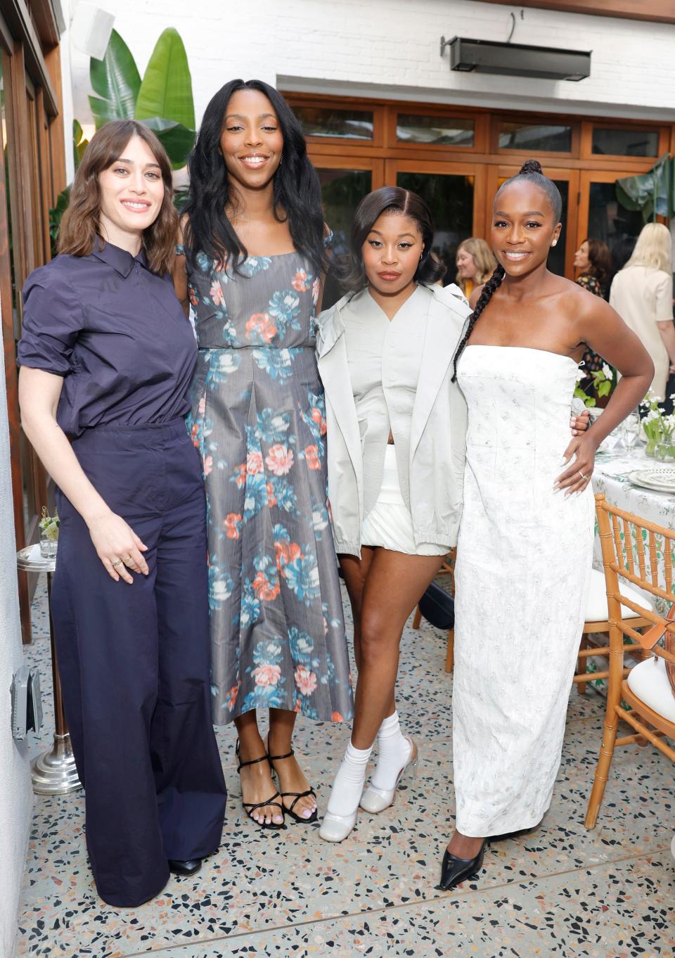 Lizzy Caplan (in Spring/Summer 2024 nylon taffeta polo and cotton poplin pant, with double-faced cotton jacket, and the Deville bag), Jessica Williams (wearing the Tory Burch double-faced wool coat, cylinder heel sandal, and Robinson patent quilted bag), Dominique Fishback and Aja Naomi King.