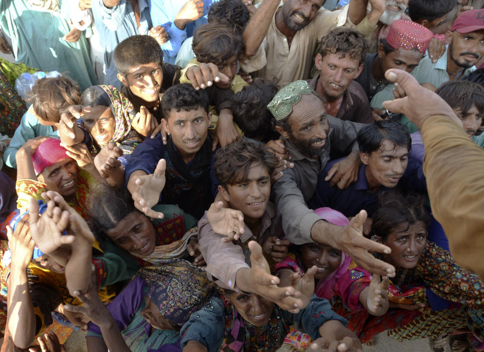 Displaced families, who fled their flood-hit homes, jostle to get relief aid distributed by soldiers of Pakistan rangers, in Dera Allahyar, in Jaffarabad, a district of southwestern Balochistan province, Saturday, Sept. 17, 2022. The devastating floods affected over 33 million people and displaced over half a million people who are still living in tents and make-shift homes. The water has destroyed 70% of wheat, cotton and other crops in Pakistan. (AP Photo/Zahid Hussain)