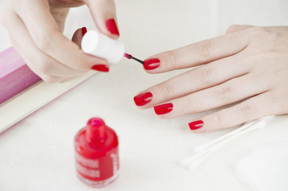 A person polishing their nails with a red color