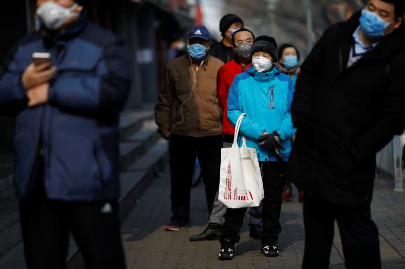 Customers wearing face masks queue for food outside a store, as the country is hit by an outbreak of the novel coronavirus, in Beijing
