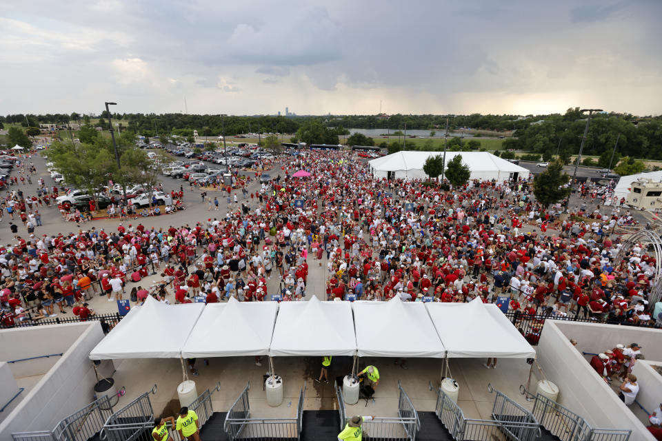 Fans wait outside the stadium during a weather delay before the first game of the NCAA Women's College World Series softball championship series between Florida State and Oklahoma on Wednesday, June 7, 2023, in Oklahoma City. (AP Photo/Nate Billings)