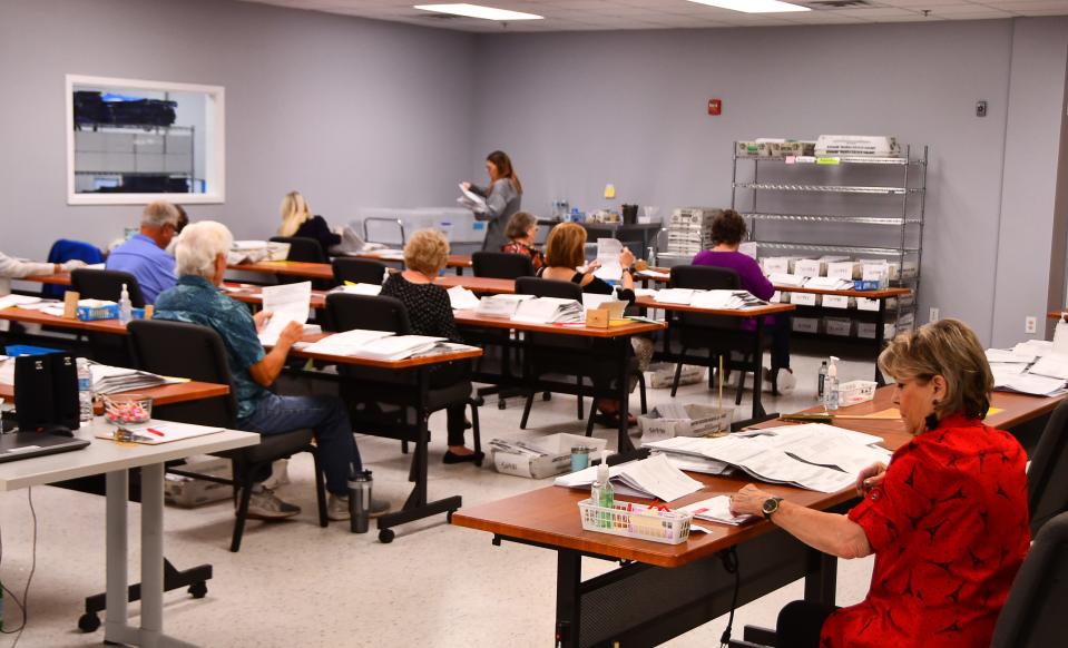 Election workers at the Elections Support Center in Melbourne were busy Monday processing mail-in ballots.