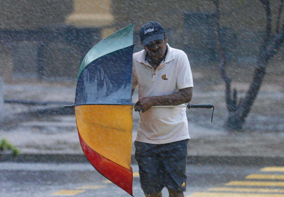 A man holds his umbrella against the high wind and rain in Colombo, Sri Lanka, May 15, 2016. (Reuters/Dinuka Liyanawatte)