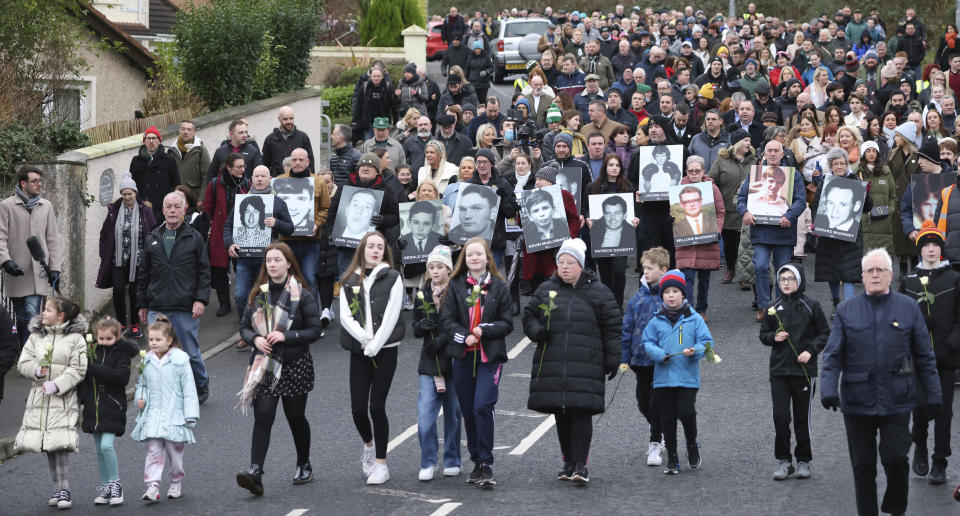 People take part in a march to commemorate the 50th anniversary of the 'Bloody Sunday' shootings with photographs of some of the victims in Londonderry, Sunday, Jan. 30, 2022. In 1972 British soldiers shot 28 unarmed civilians at a civil rights march, killing 13 on what is known as Bloody Sunday or the Bogside Massacre. Sunday marks the 50th anniversary of the shootings in the Bogside area of Londonderry .(AP Photo/Peter Morrison)