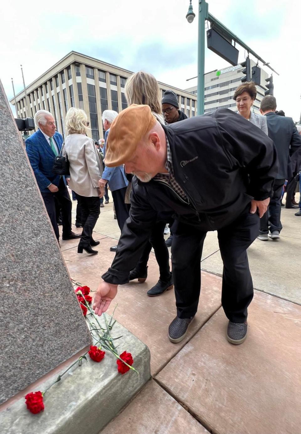 An attendee places a carnation at the base of a statue of President William McKinley at its unveiling on Saturday in front of the Stark County Courthouse.