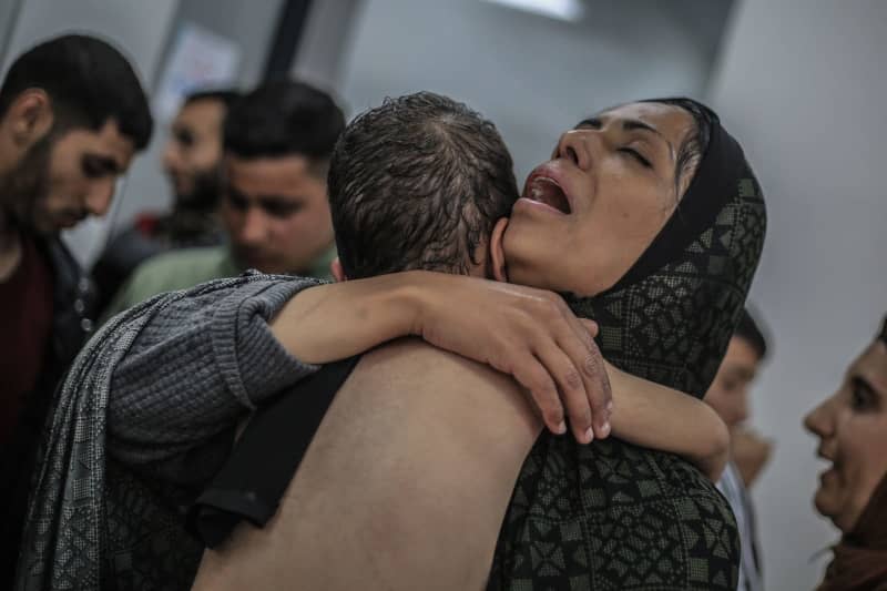 A Palestinian woman hugs a child in Kuwait hospital after she was injured in an Israeli airstrike near displaced persons camps. Mohammed Talatene/dpa