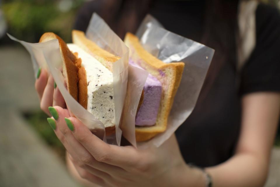 A close-up shot of a woman's hands, holding two traditional ice cream sandwiches.