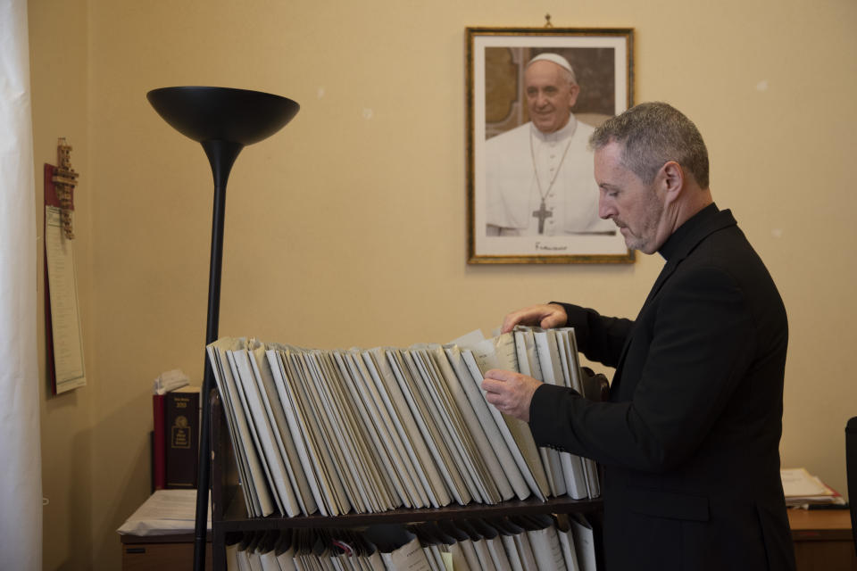 In this Monday, Dec. 9, 2019 photo, Monsignor John Kennedy, the head of the Congregation for the Doctrine of the Faith discipline section, looks through files at his office during an interview at the Vatican. The Vatican office responsible for processing clergy sex abuse complaints has seen a record 1,000 cases reported from around the world this year, including from countries it had not heard from before, suggesting that the worst may be yet to come in a crisis that has plagued the Catholic Church. (AP Photo/Alessandra Tarantino)