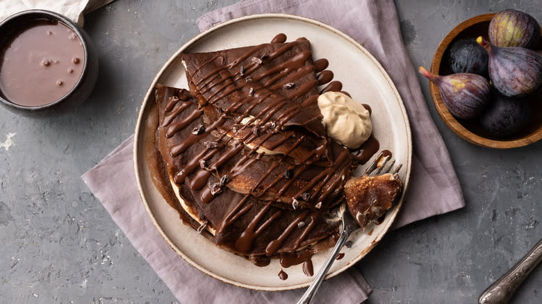 plate of chocolate crepes with chocolate sauce and whipped cream