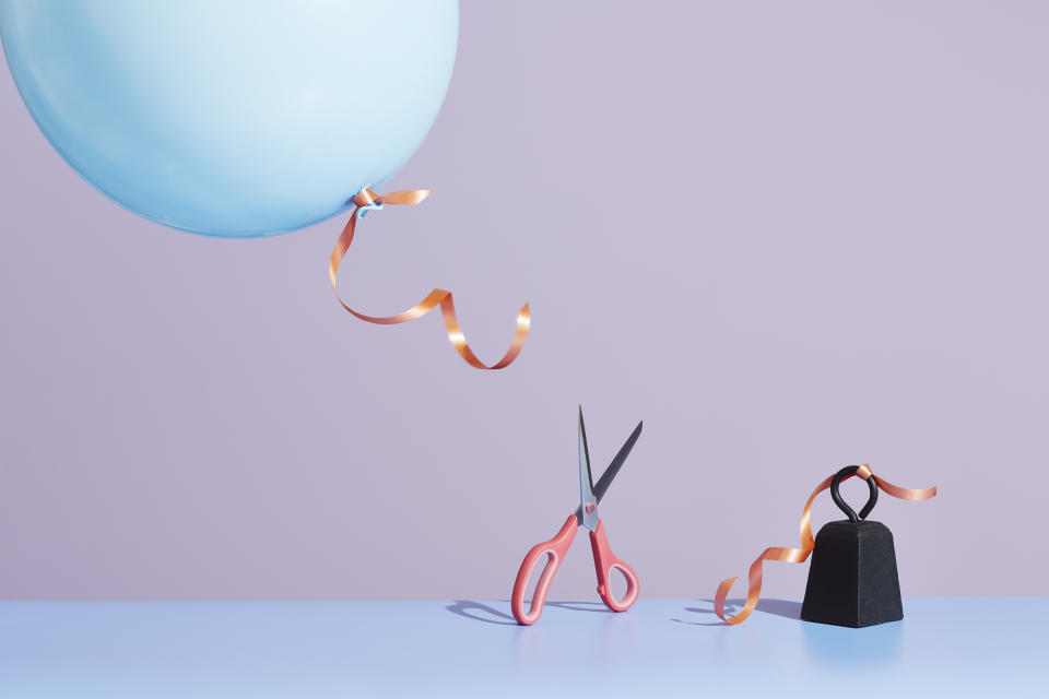 Image of a pair of scissors cutting a string affixed to a metal weight.