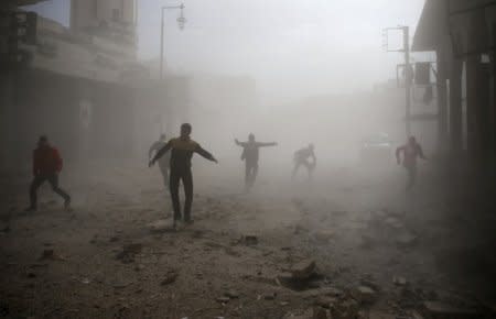 FILE PHOTO: Civil defence members and civilians are seen running after an air raid in the besieged town of Douma in eastern Ghouta in Damascus, Syria, February 6, 2018. REUTERS/ Bassam Khabieh